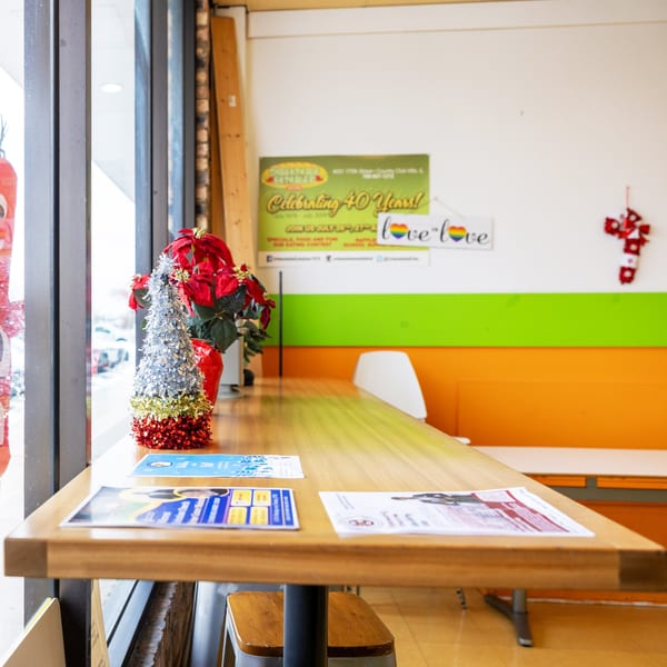 A long wooden counter with holiday decorations and flyers, next to a window overlooking a snowy street.